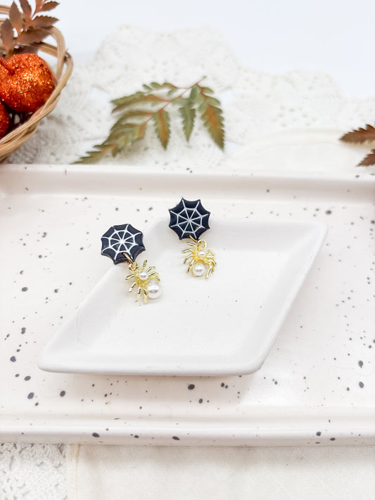 Pearl spiders dangling from webs